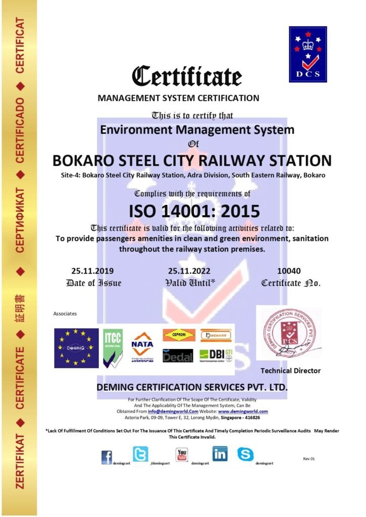 Management System Certificate issued by Deming Certification Services Pvt. Ltd. certifying Bokaro Steel City Railway Station (Adra Division, South Eastern Railway, Bokaro) for ISO 14001:2015 Environment Management System compliance, featuring a vertical gold margin on the left and international accreditation logos along the bottom.